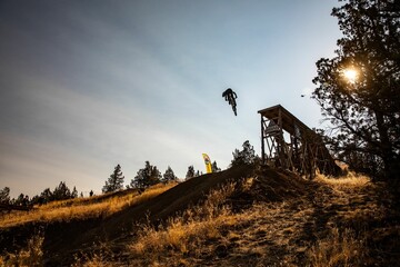 Silhouette of a biker in the air over the slope of a hill