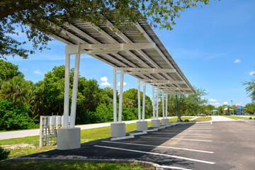 Solar panels installed as shade roof over parking lot for parked electric cars for effective generation of clean electricity. Photovoltaic technology integrated in urban infrastructure © bilanol