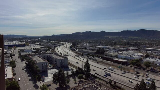 aerial footage of cars and trucks driving along interstate 5 surrounded by office buildings and apartments with mountain ranges and green trees in Burbank California USA