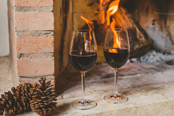 Taças de vinho tinto em lareira no inverno com pinhas