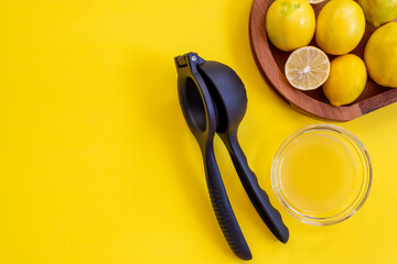 Lemon juicer, lemon juice and lemons on a yellow background