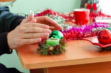 Close-up of freezing male hands warming up with flame of candle at cold Christmas Day during energy...