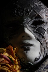 Venetian carnival mask with rdry rose close up on dark background