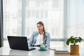 Frustrated and angry freelancer businesswoman talking on video call, woman arguing and looking at laptop screen, online business conference. Female in smart casual wear sitting at office desk