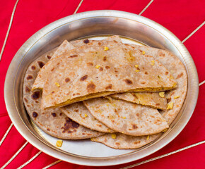 Dal paratha or chana dal stuffed paratha in copper plate in red background.