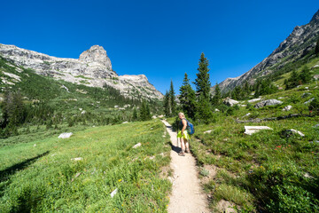 Fototapeta na wymiar Woman backpacker hikes along the Cascade Canyon trail in Grand Teton National Park, looking angry and upset