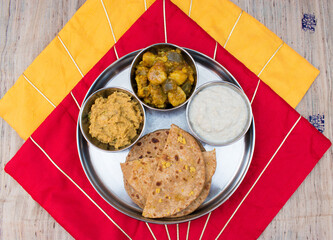 Dal Puri or dal stuffed paratha in plate and Gur kheer, Payasam, Phirni or rice pudding, mixed veg called dalna sabzi and oal chutney. Bihari thali . top view