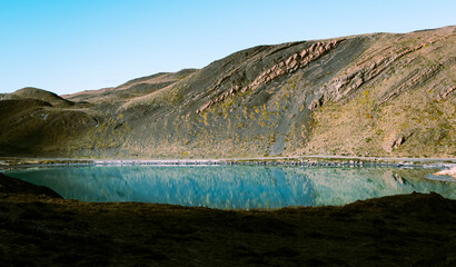 lago de color turquesa entre montes y cerros rocosos, paisaje hermoso con cielo azul 