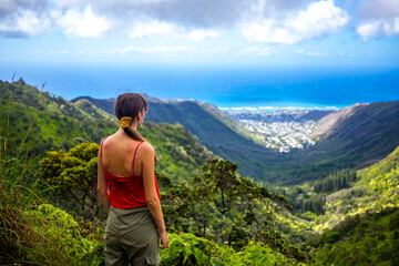 Naklejka premium hiker girl enjoys the panorama of oahu island and honolulu in hawaii islands while climbing wiliwilinui ridge trail; hiking on green mountains in hawaii, holidays in hawaii