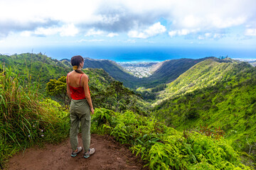 Fototapeta na wymiar hiker girl enjoys the panorama of oahu island and honolulu in hawaii islands while climbing wiliwilinui ridge trail; hiking on green mountains in hawaii, holidays in hawaii