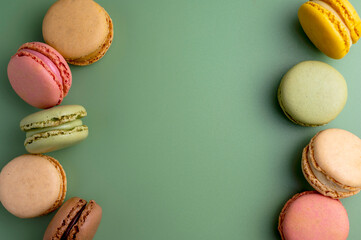 Macaroons colorful cookies. Macarons in bowl, french sweet dessert, top view, green background. Copy space.