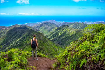 hiker girl enjoys the panorama of oahu island and honolulu in hawaii islands while climbing wiliwilinui ridge trail; hiking on green mountains in hawaii, holidays in hawaii - obrazy, fototapety, plakaty