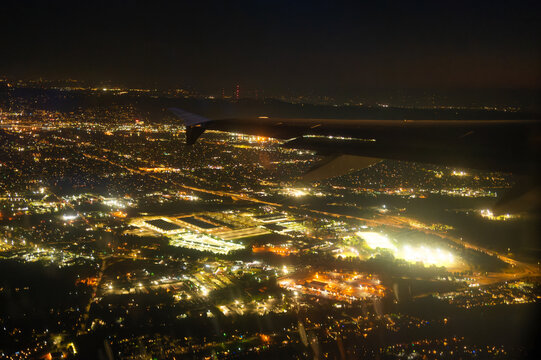 A large night city illuminated by lights from an airplane window from a bird's eye view. Fantastic spectacle. Map, infrastructure, topography, tourism, travel.