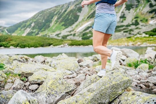 Beautiful blond woman is running in the mountains on rocks and stones. Playing sports in the Polish Tatra Mountains.