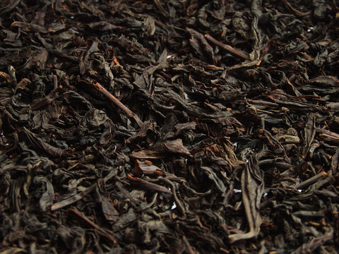 Black large-leaf tea as a background. Texture of dry black tea leaves. Dark background. black leaf tea close up