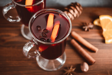 Mulled red wine in a glass and spices on wooden background
