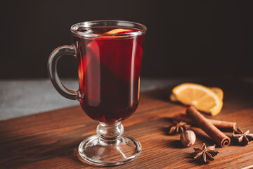 Mulled red wine in a glass and spices on wooden background