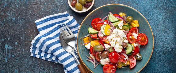 Greek fresh healthy colorful salad with feta cheese, vegetables, olives in blue ceramic bowl on rustic concrete background top view, Mediterranean diet, traditional cuisine of Greece 