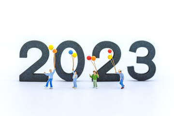 2023 New Year Kid and Family Concept. Closeup of group of children walking and playing with balloon with wooden number on white background.