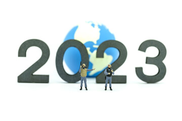 2023 Global Business and security New Year Concept. Closeup of group of soldier  miniature figures with machine gun standing with wooden number and mini world ball on white background.