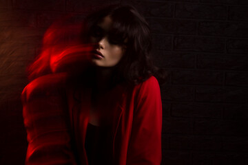 Closeup portrait of a girl with makeup and hairstyle, wear red suit, with closed eyes, red studio light and effects.