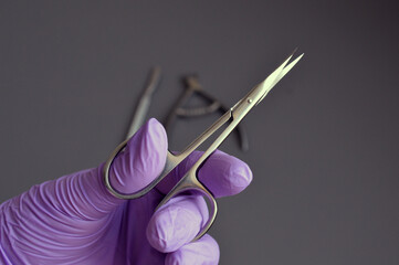 Manicure tools are held by a manicurist in rubber gloves