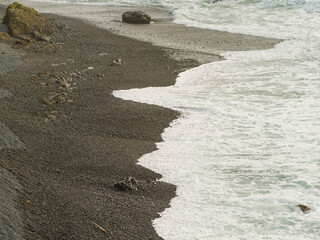 Sea coast. White foamy waves crash on the shore. Monochrome image. The beauty and grandeur of pristine nature. Ecology, weather, sea recreation, beauty of nature.
