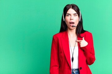 looking shocked and surprised with mouth wide open, pointing to self. telemarketer with a headset...