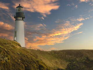 Panoramic shot. A beautiful white lighthouse on a high green ocean shore against a dramatic sky with pink clouds. Twilight. Beautiful nature, romance, tourism, travel destination advertising.
