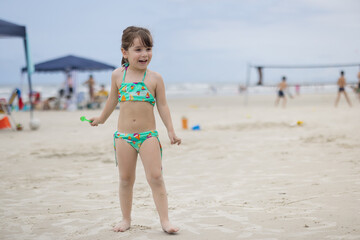 garotinha de 3 anos brincando na praia