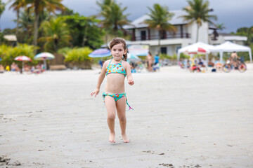 garotinha de 3 anos brincando na praia