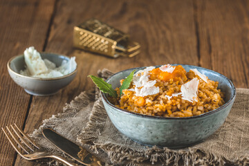 Homemade pumpkin risotto with parmesan cheese on a rustic wooden table