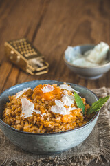 Homemade pumpkin risotto with parmesan cheese on a rustic wooden table
