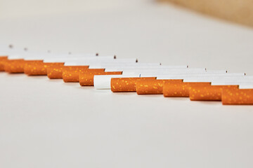 Cigarettes lie in a row on the table. Cigarette road. One cigarette is different from the others