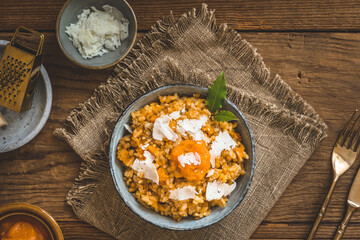 Homemade pumpkin risotto with parmesan cheese on a rustic wooden table