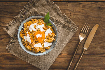 Homemade pumpkin risotto with parmesan cheese on a rustic wooden table