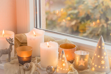 Christmas decorations in a window with glitter reindeer and various candles and glasses