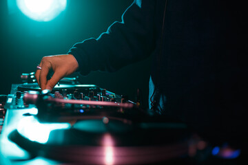 Hip hop dj plays music on party in night club. Disc jockey adjusting volume and frequency...