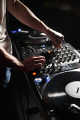 Fototapeta na wymiar Techno DJ plays set with vinyl turn table and sound mixer in night club. Professional disc jockey mixing records on turntables