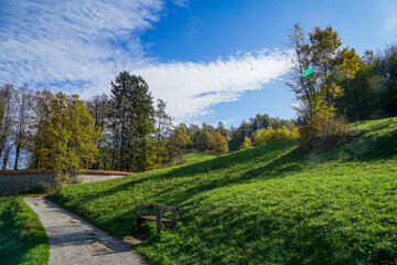 Fototapeta na wymiar Beautiful hiking trail leads through idyllic landscape in slovenia near Skofja Loka. Green meadow. Green meadow, blue sky and autumnal trees. 