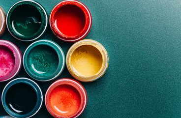 Beautiful, bright, mother-of-pearl, multicolored open cans of paint on a blue background. View from...