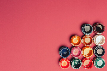 Beautiful, bright, mother-of-pearl, multicolored open cans of paint on a bright pink background....
