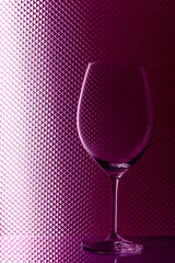 One empty wine glass on a pink gradient abstract background.