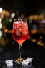cocktail with ice cubes on black bar counter