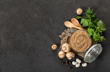 Vegan appetizer. Bean mushroom pate in a glass jar on a linen napkin. Dark gray background. Rustic style. Copy space