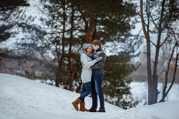 Fototapeta na wymiar The couple hugs and smiles while standing in the snow.