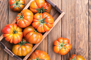 Red ugly tomatoes on a wooden background, closeup. Funny tomatoes, ugly vegetable, view from above. Organic gardening