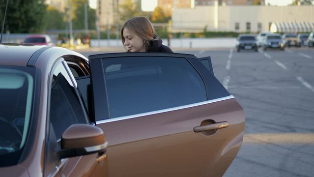 Woman funny trying to put purchased modern tv in car trunk at store parking in close-up, delivery concept