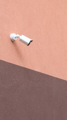 Naklejka premium Surveillance camera on a two-tone wall. Security home equipment house safe concept