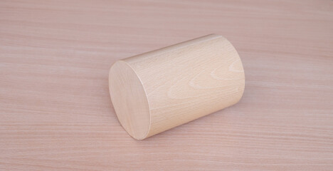 Wooden roller cylinder geometric model shape on wood table background. Perfect geometry concept